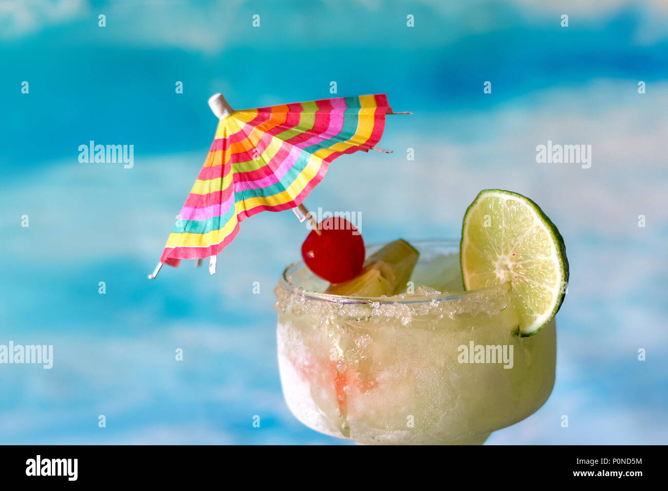 Frozen margarita Getränke mit Kalk und Kirsche garnieren und einen farbenfrohen Drink Regenschirm Stockfoto