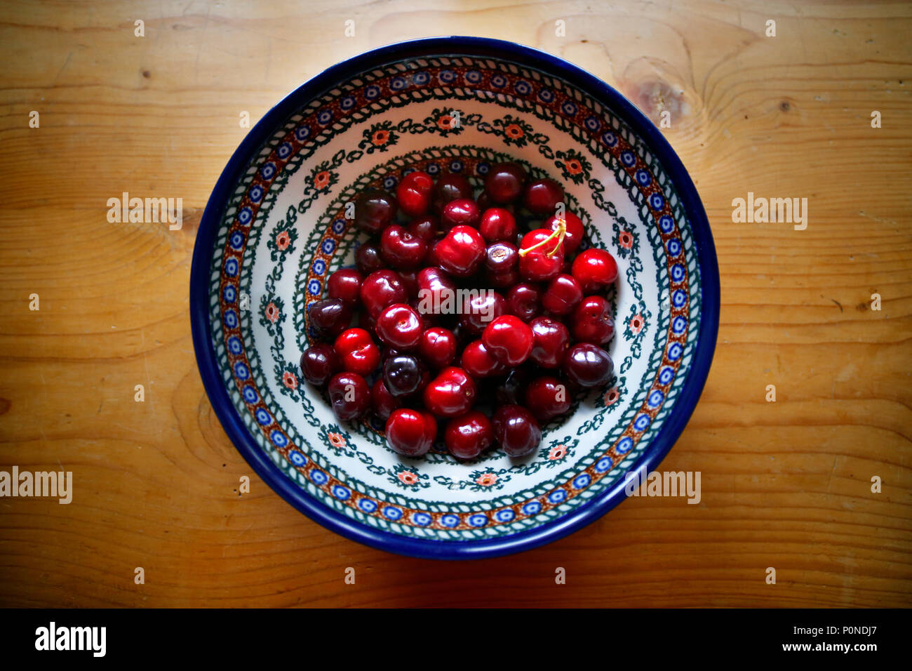 Schale mit Kirschen auf einem alten Kiefer Tisch. Stockfoto