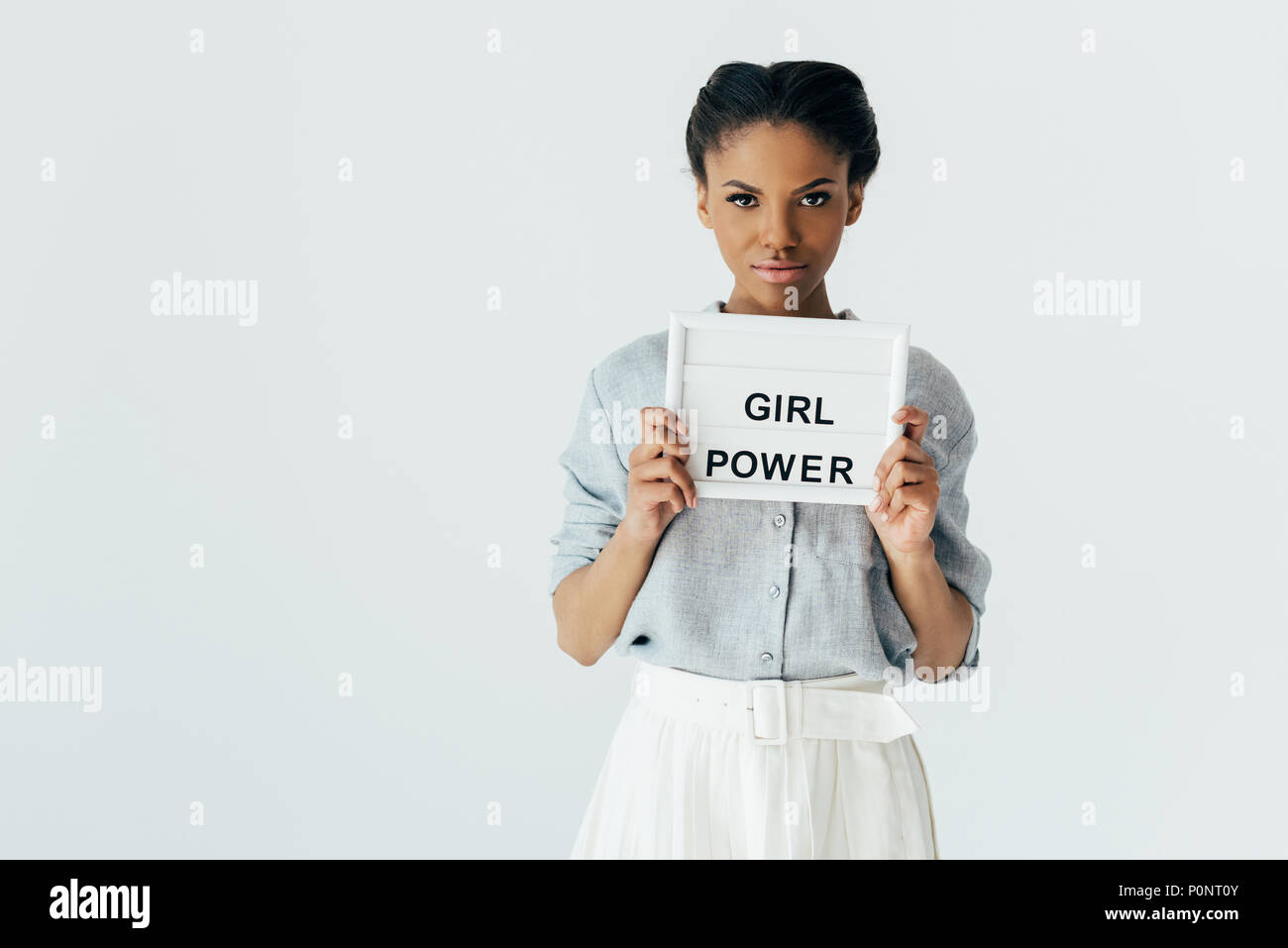 Portrait der afrikanischen amerikanischen Frau mit Girl Power Board in die Hände an der Kamera isoliert auf Grau suchen Stockfoto