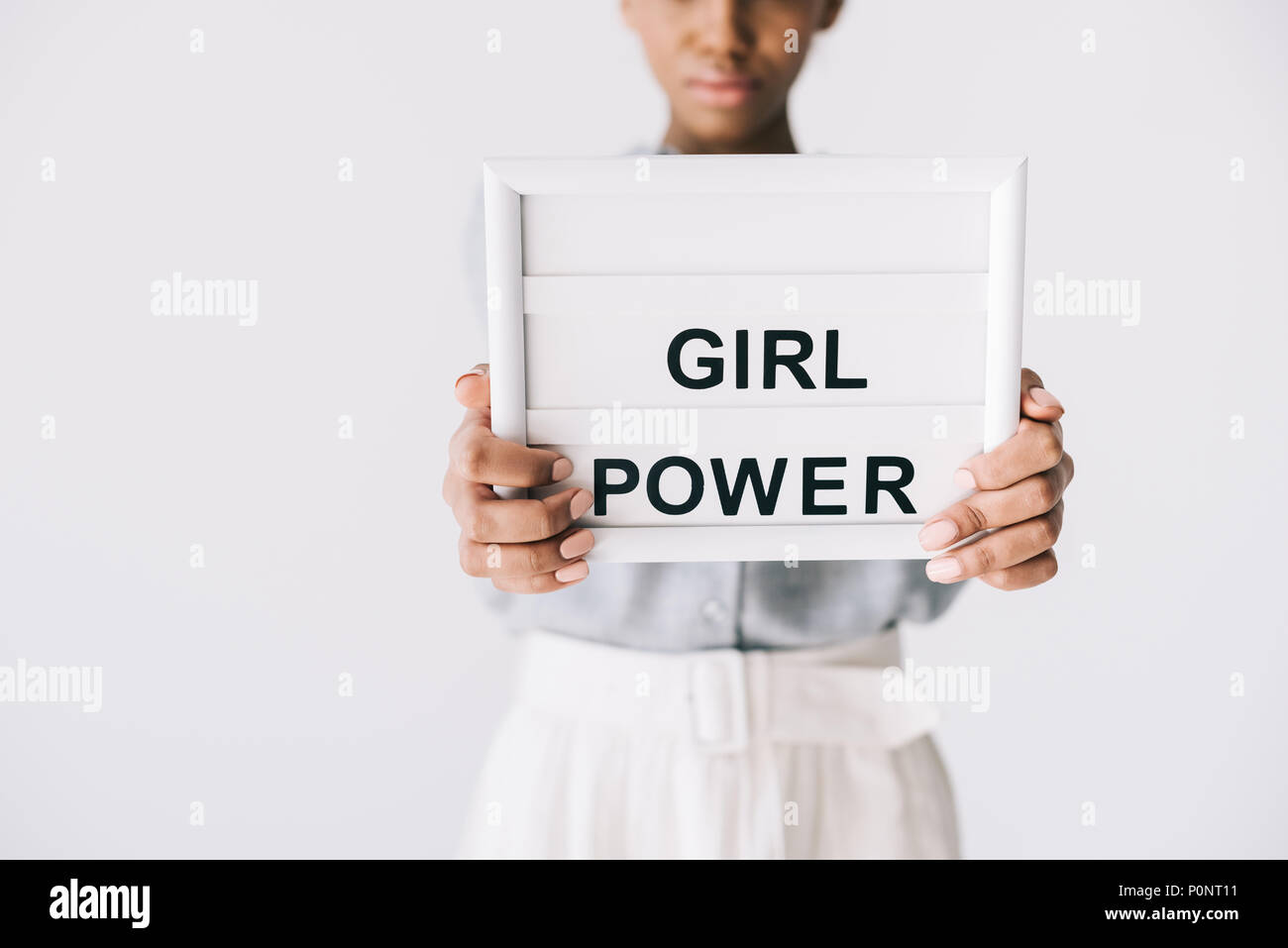 Selektiver Fokus der afrikanischen amerikanischen Frau, Girl Power Board in den Händen isoliert auf Grau Stockfoto