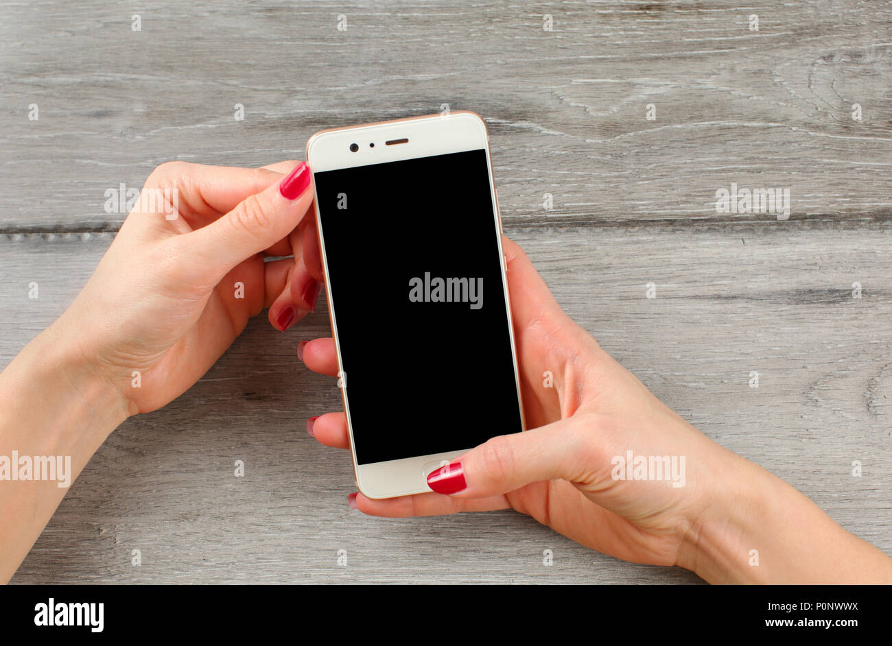 Ansicht von oben auf die junge Frau Hände, mit roten Nägeln, Holding weißen Smart Phone. Schwarzer Bildschirm wählen Sie Ihr Bild oder Text hinzufügen. Stockfoto