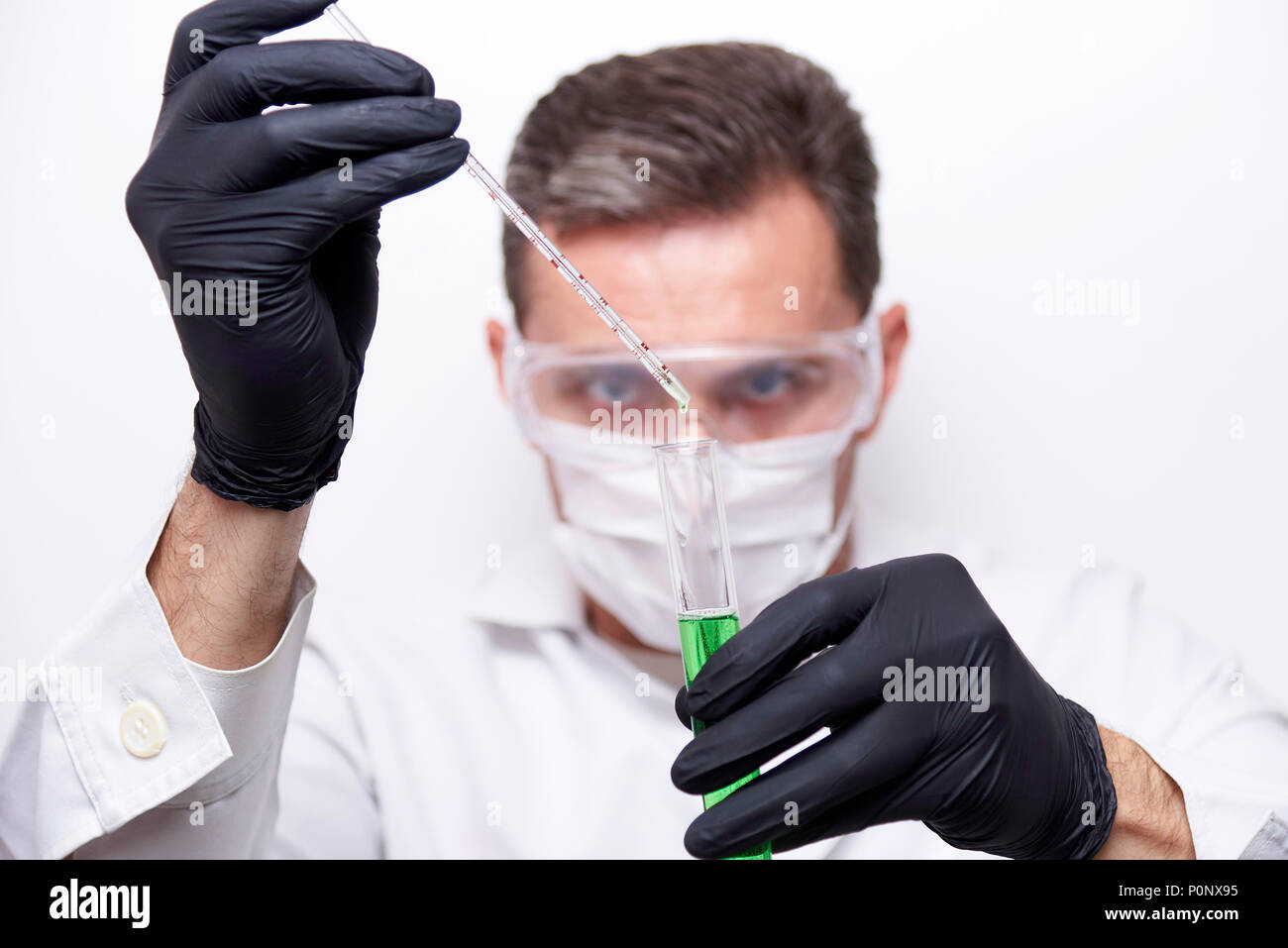 Ein Reagenzglas mit einer grünen Flüssigkeit in die Hände eines Wissenschaftlers Chemiker ist auf einem weißen Hintergrund. Das Experiment ist durch einen Wissenschaftler tragen durchgeführt Stockfoto