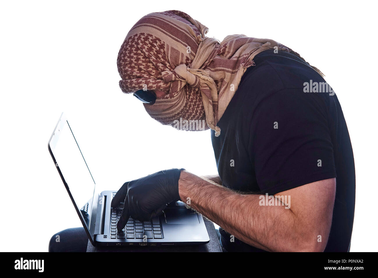 Der Mann unter dem arafatka und schwarzer Brille versteckt hält seine Hände in schwarz Handschuhe auf dem Laptop. Stockfoto