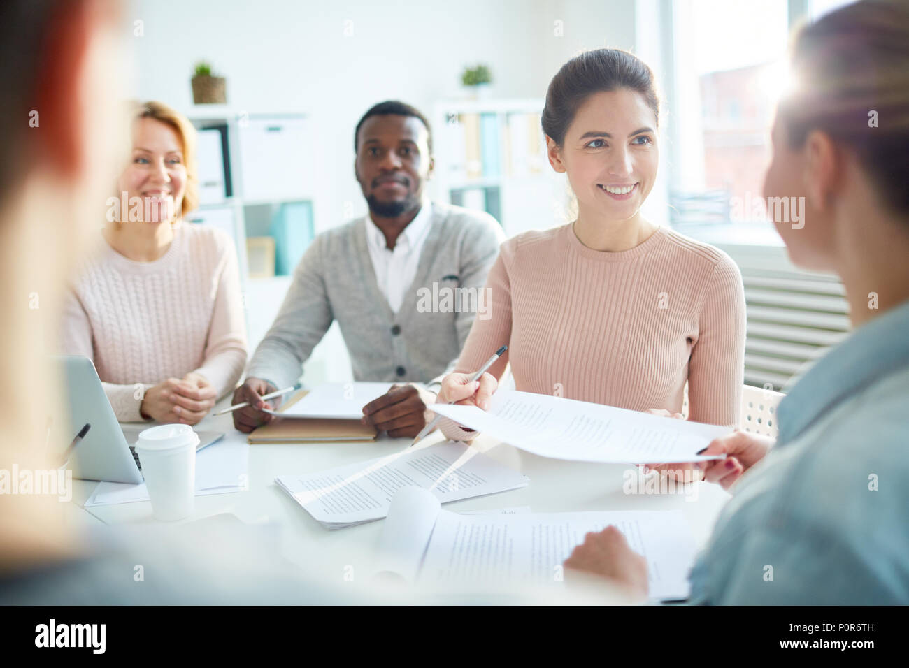 Freudige multi-ethnischen Team der weißen Arbeiter in produktive Projekt Diskussion beim zusammen an modernen Großraumbüro versammelt, lens flare Stockfoto