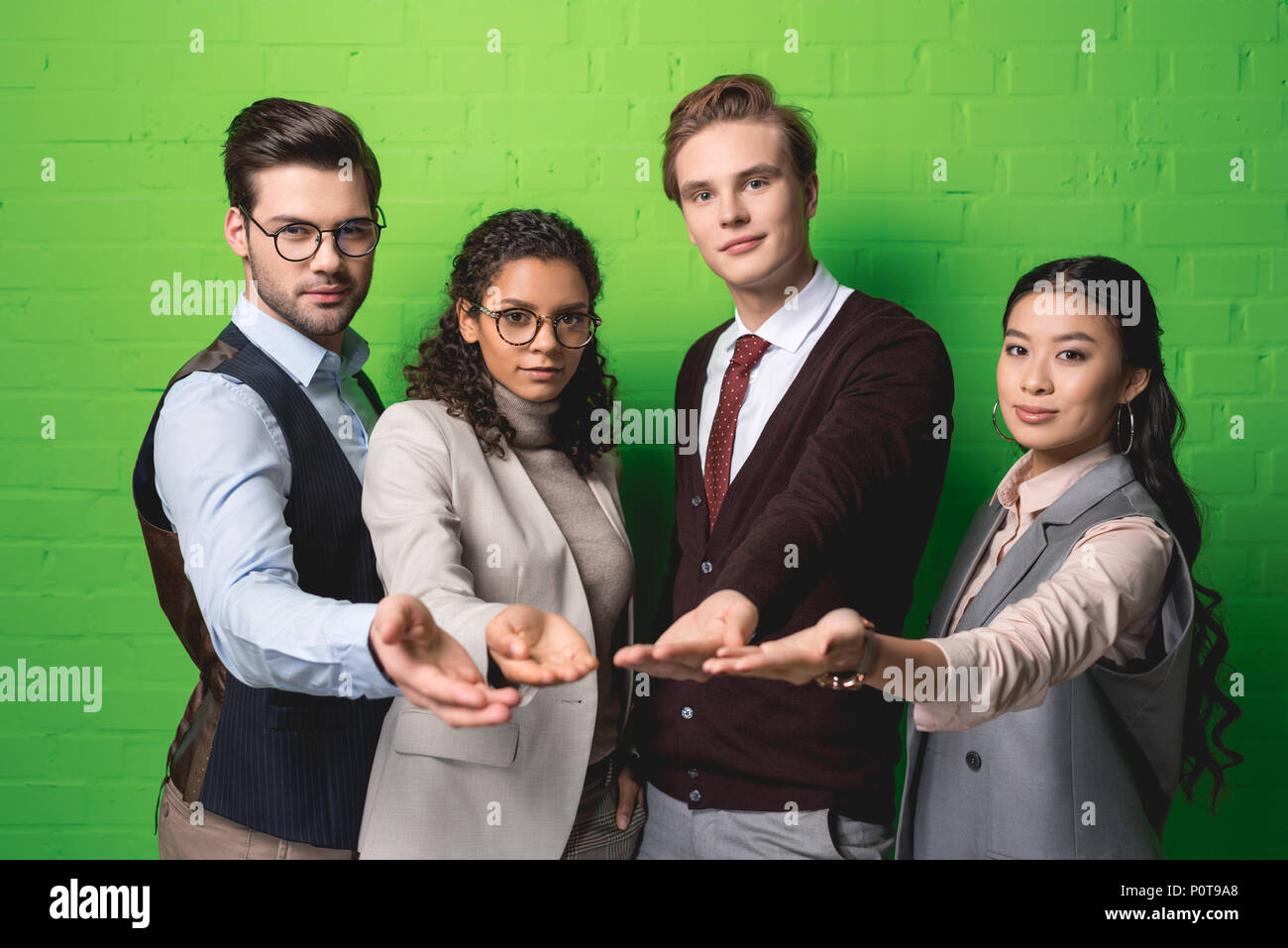 Multikulturelle Geschäftsleute bittet um Almosen vor der grünen Wand Stockfoto