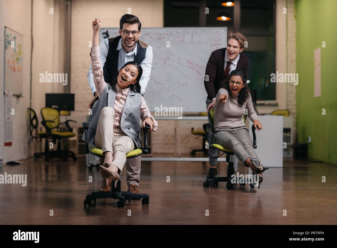 Lächelnd multiethnischen Geschäftsleute haben sie Spaß mit Drehstuhl im Büro Stockfoto