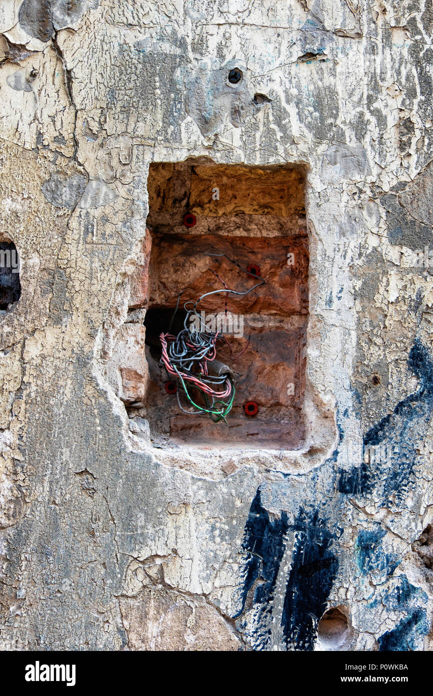 Gebäudewand abstrakt. Verwitterte & alte Mauer mit freiliegenden elektrischen Kabel gerissen Stockfoto