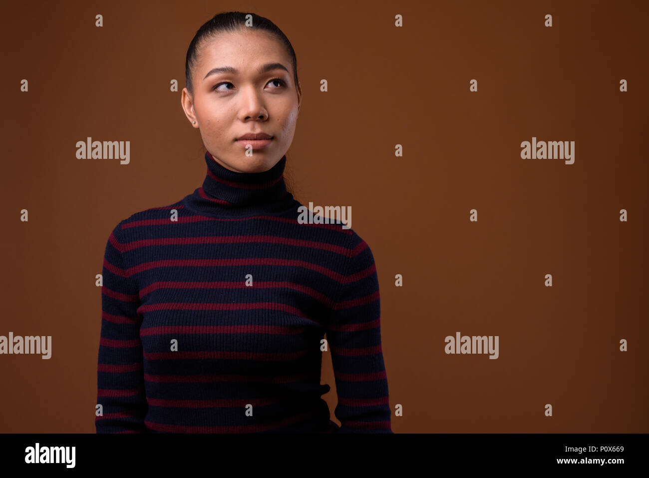 Junge schöne asiatische transgender Frau gegen braunen Hintergrund Stockfoto