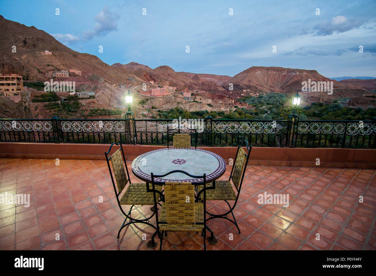 Tisch mit 4 Stühlen auf der Terrasse in Dades Tal in der Nähe von Boumalne Dades Dorf in Marokko. Blaue Stunde shot mit Bergen im Hintergrund Stockfoto
