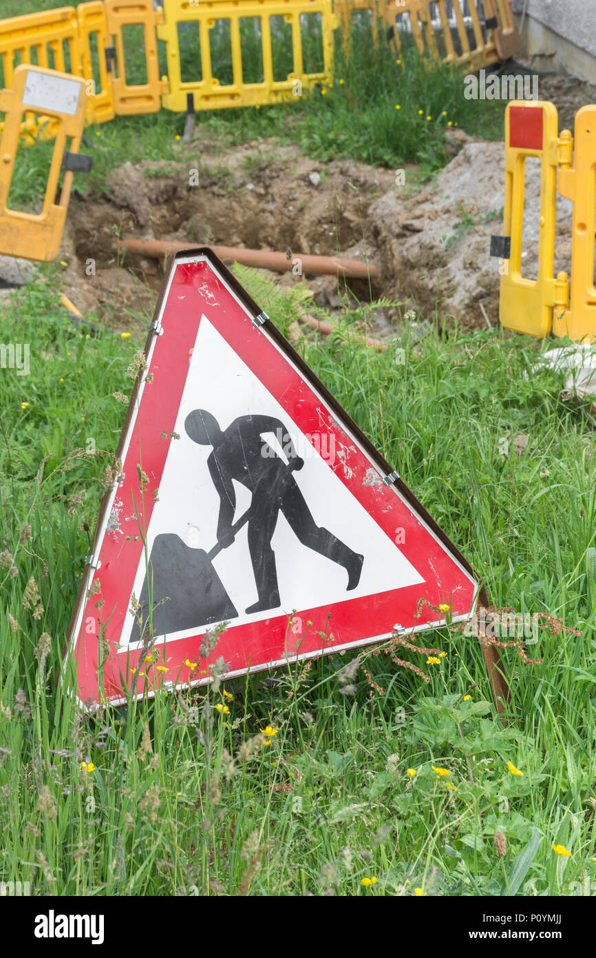 Männer an der Arbeit am Straßenrand Werke Warnschild mit Ausgrabungen in den Hintergrund. Konzept Straßenarbeiten, Männer an der Arbeit Piktogramm, öffentliche Warnzeichen. Stockfoto