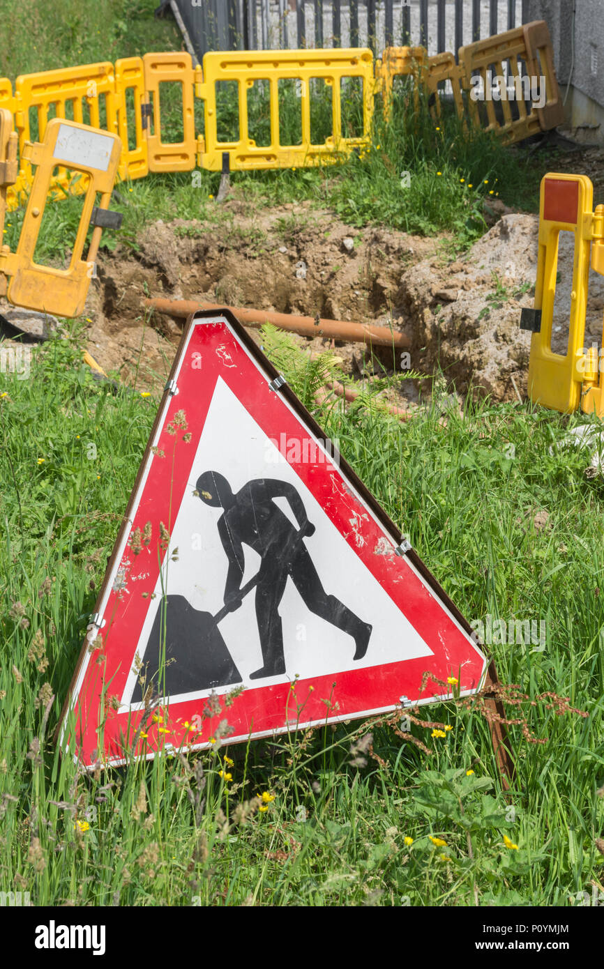 Männer an der Arbeit am Straßenrand Werke Warnschild mit Ausgrabungen in den Hintergrund. Konzept Straßenarbeiten, Männer an der Arbeit Piktogramm, öffentliche Warnzeichen. Stockfoto