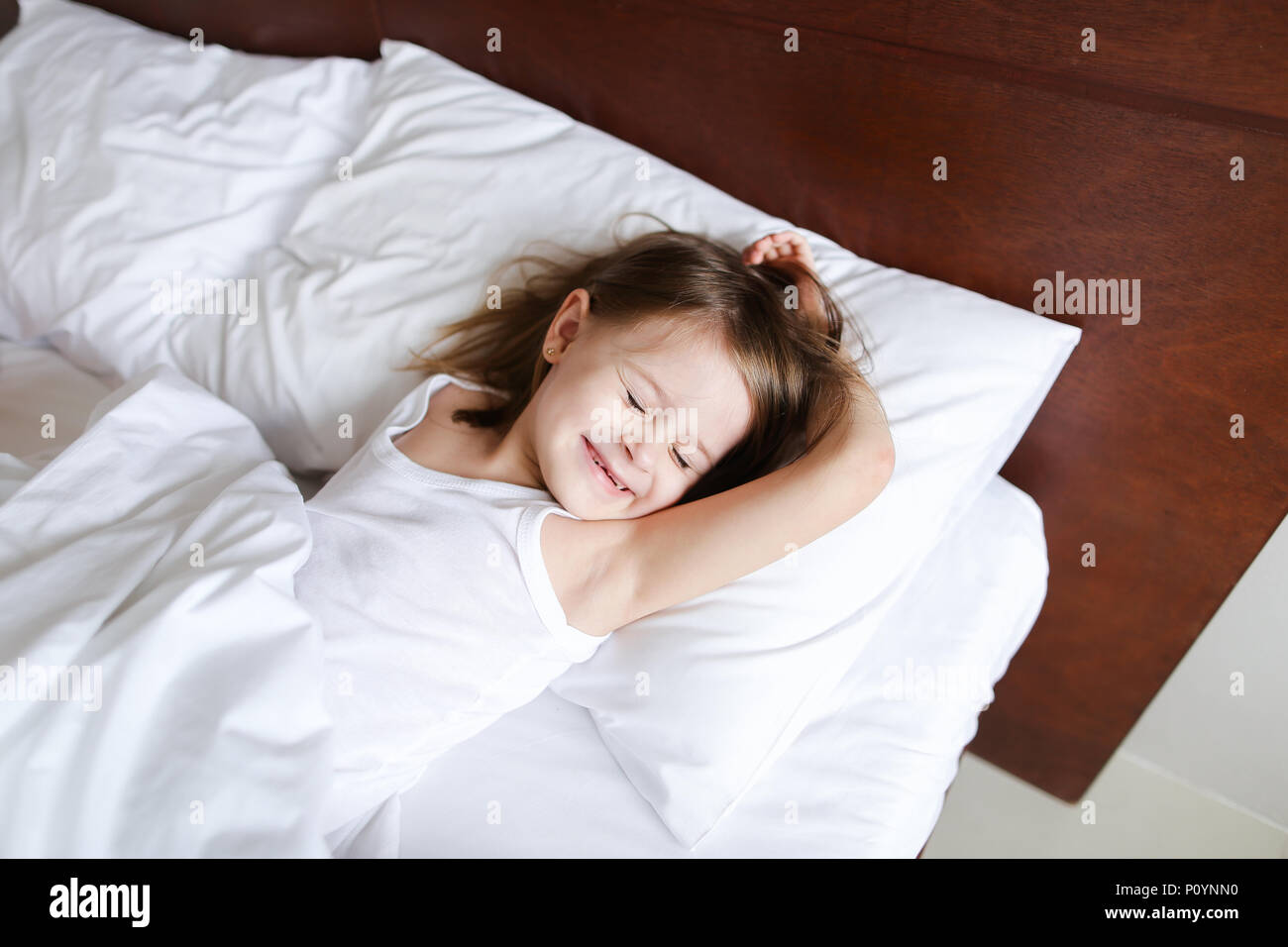 Wenig kaukasische Mädchen schlafen am Morgen vor der Schule auf dem Bett  mit weißer Bettwäsche Stockfotografie - Alamy
