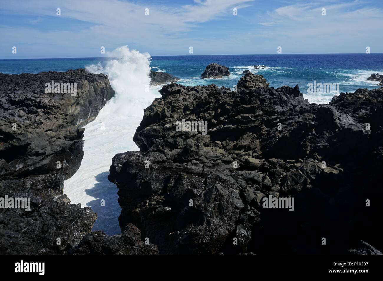 Ein schöner Absturz Welle in einem lava Canyon am Ufer an der Küste von La Reunion, Frankreich an einem heißen Sommer Tag windig Stockfoto