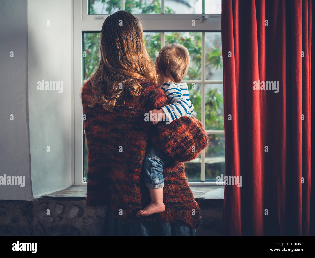 Eine junge wmother ist Blick aus dem Fenster mit Ihrem kleinen Kind Junge Stockfoto