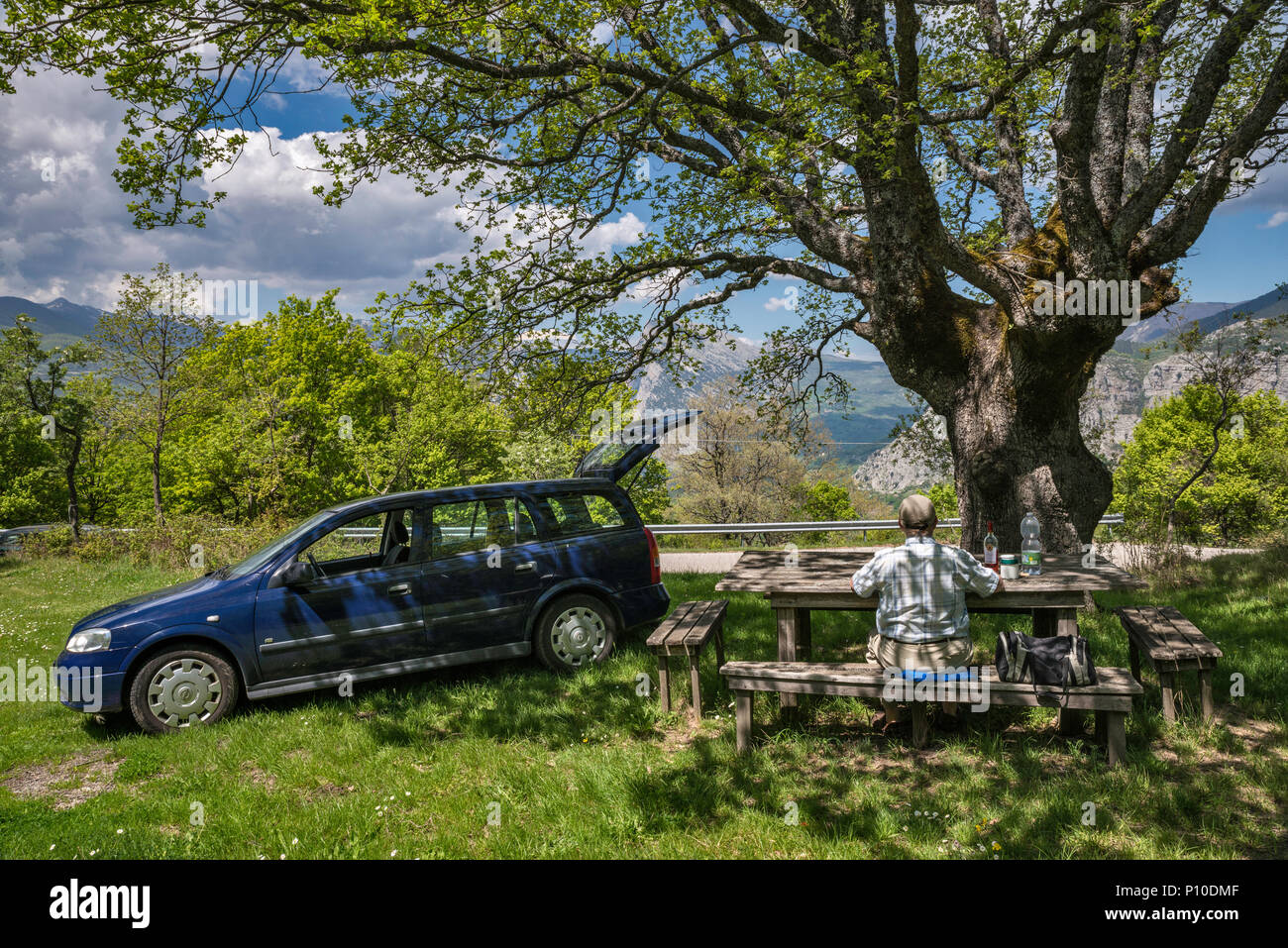 Mann in seinem 60s Picknicken am Straßenrand Tisch in der Nähe der Stadt San Lorenzo Bellizzi, südlichen Apennin, Nationalpark Pollino, Kalabrien, Italien Stockfoto