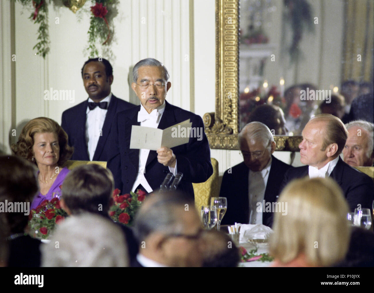 Kaiser Hirohito liest einen Toast auf den Staat Abendessen in seiner Ehre gehalten, und die Kaiserin Nagako's, während ihres ersten offiziellen Staatsbesuch in den Vereinigten Staaten. Außerdem abgebildet sind erste Dame Betty Ford, ein Kellner, ein Dolmetscher, und Präsident Gerald R. Ford. Oktober 2, 1975. Stockfoto