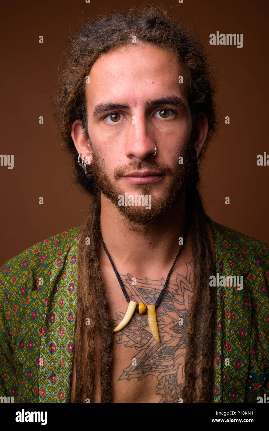 Junge schöne Hispanic Mann mit Dreadlocks gegen Braun backgr Stockfoto