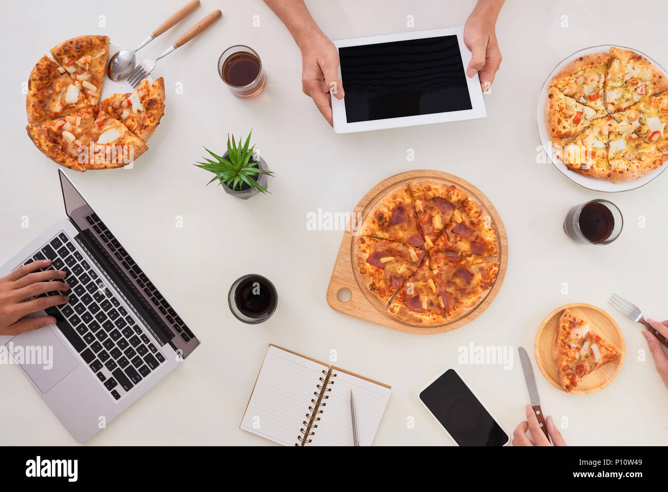 Die Angestellten essen Pizza und trinken Kaffee im Büro. Sie haben einen Bruch in ihrer Arbeit. Sie ruhen. Stockfoto