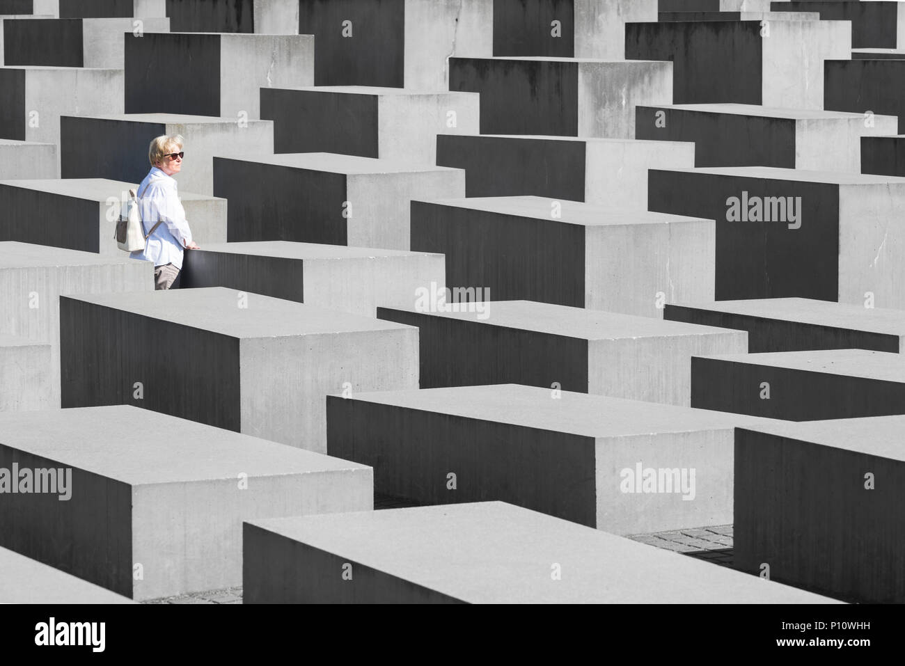 Nachdenkliche Messe behaarte Frau in weißen Kleidern zwischen den Bausteinen der Holocaust Mahnmal, Berlin, Deutschland Stockfoto