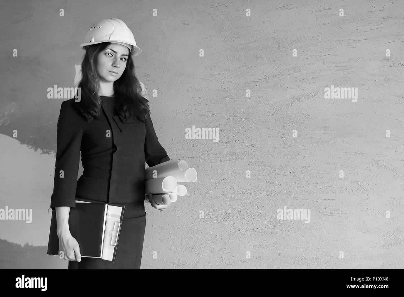 Weibliche Architekt auf der Baustelle mit Zeichnungen und ein Notebook Stockfoto