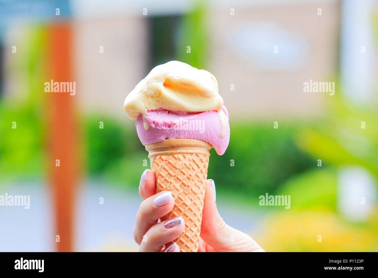 Weibliche hand Eis in der Waffel Kegel gegen blur Hintergrund Stockfoto