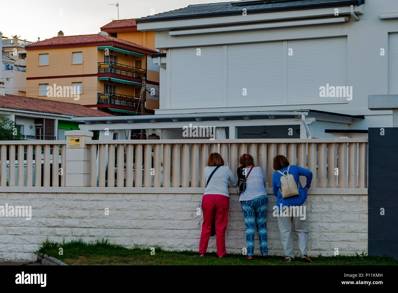 Drei spanische Frauen peer durch eine Wand in einem Garten in der Axarquía, La Cala del Moral Gemeinde von Rincón de la Victoria, Malaga, Spanien Stockfoto