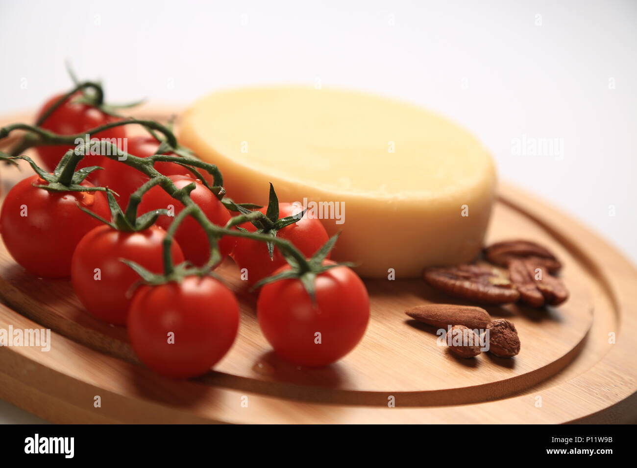 Kleiner Käse Rad neben Kirschtomaten Stockfoto