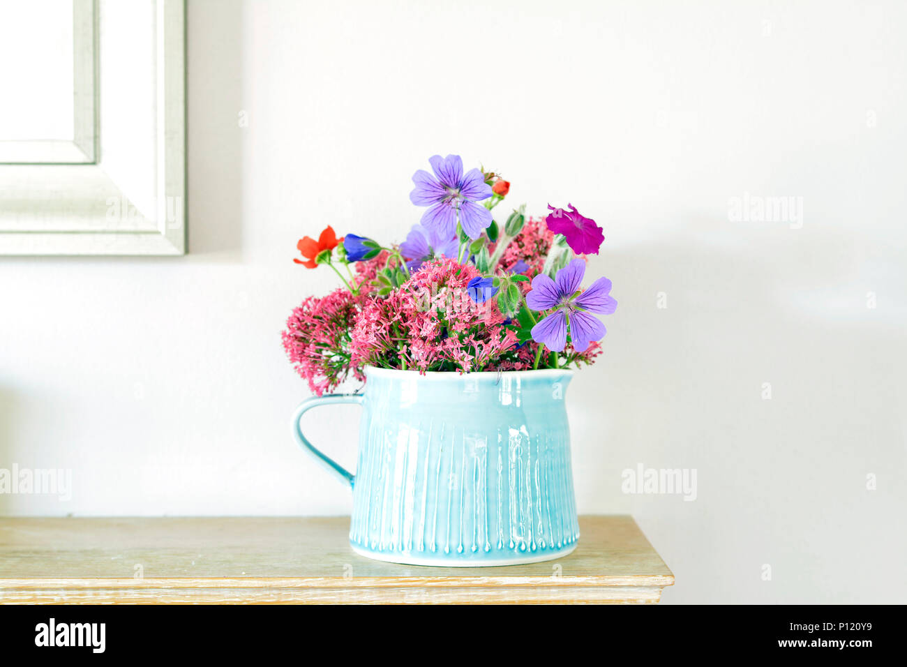 Blau steinzeug Krug mit hübschen Garten Blumen auf einem kaminsims Stockfoto