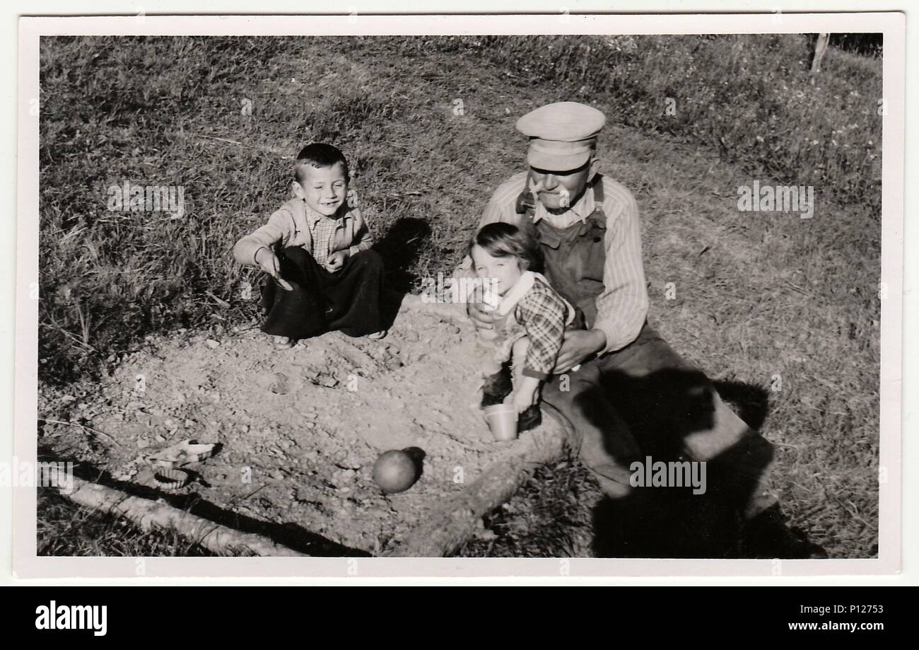 Die tschechoslowakische Republik - ca. 1940 s: ein Vintage Foto zeigt  Großvater spielt mit Kindern am Sandkasten. Antik schwarz & weiß Foto zeigt  Fotograf Schatten Stockfotografie - Alamy