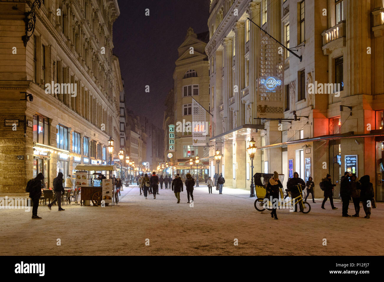 Fußgänger gehen auf einem schneebedeckten Vaci utca in Budapest im Winter bei Nacht Stockfoto