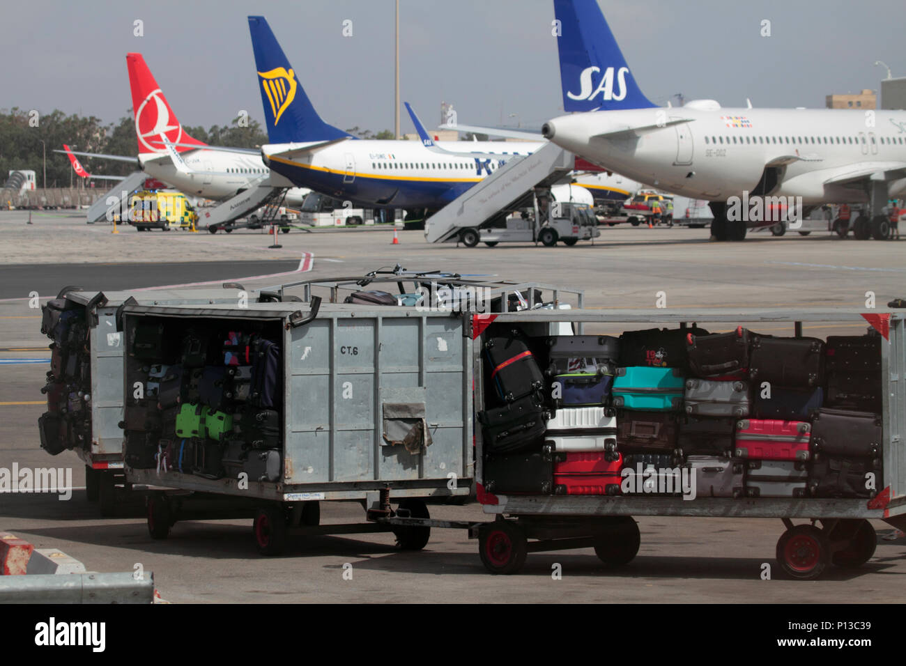 Gepäckwagen am Flughafen warten darauf, zu einem Flugzeug auf dem Vorfeld in Malta abgeschleppt zu werden. Gepäckabfertigung an Flughäfen in der EU. Flugreisen. Stockfoto