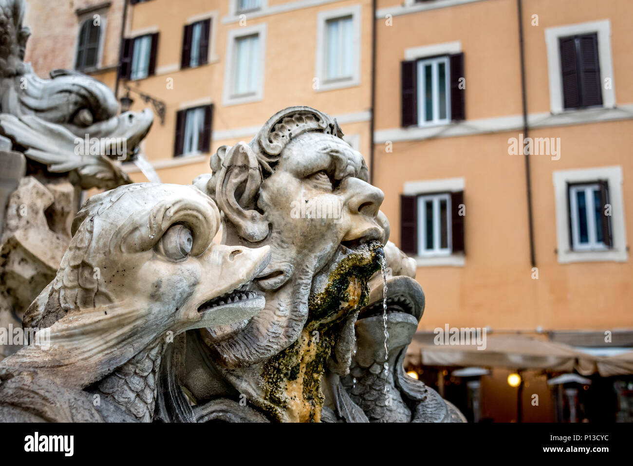 Mythische Figuren von Triton und Meerestiere an der Fontana del Moro/Moor Brunnen auf der Piazza Navona, Rom; orange Wand, Fenster mit Rollläden Stockfoto