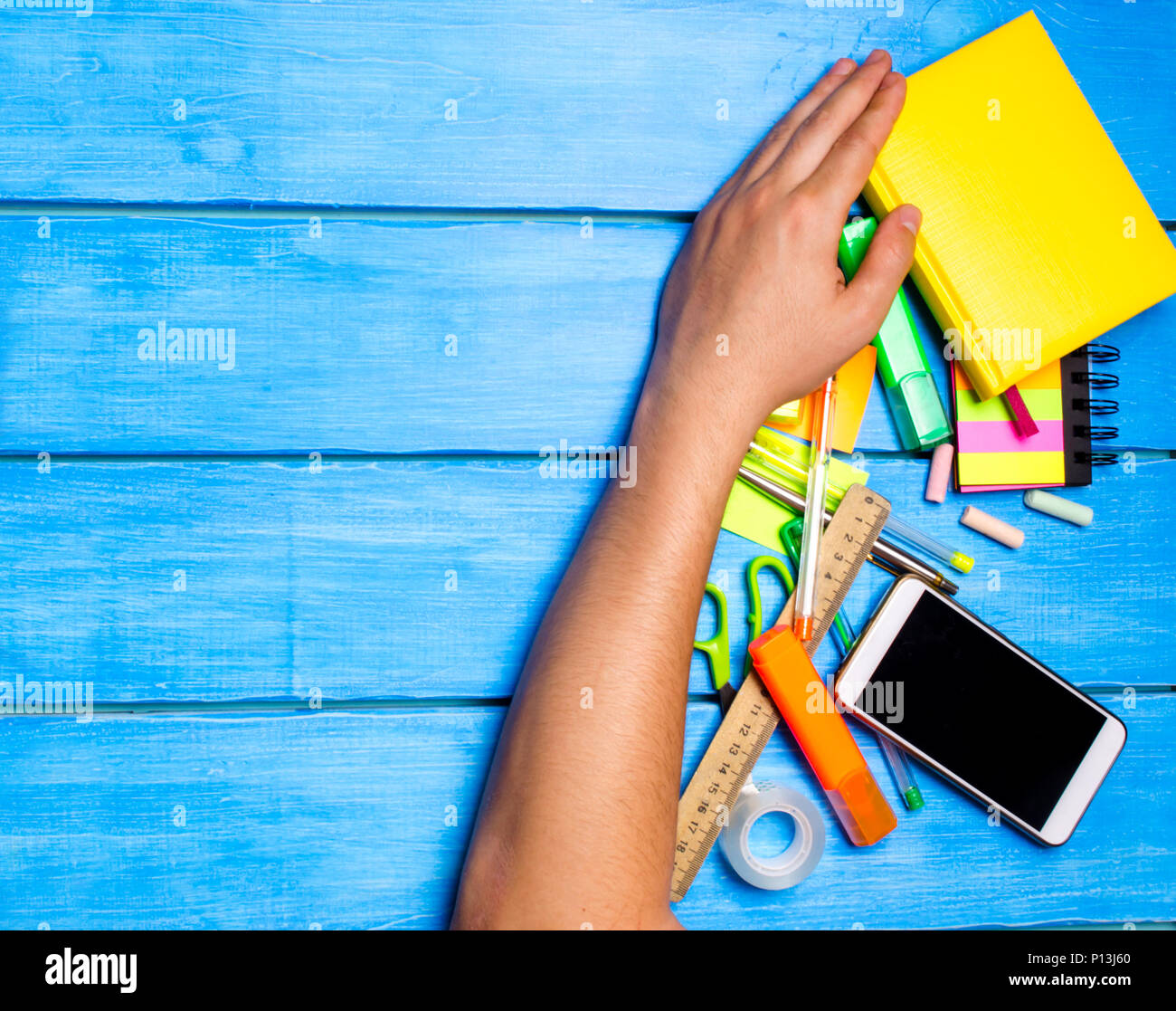 Schülerinnen und Schüler Hand reinigt entfernt die Schule liefert auf Blau Holztisch Hintergrund. Student bevorzugt andere Aufgaben auszuführen. hand Sachen weg fegt. Stockfoto