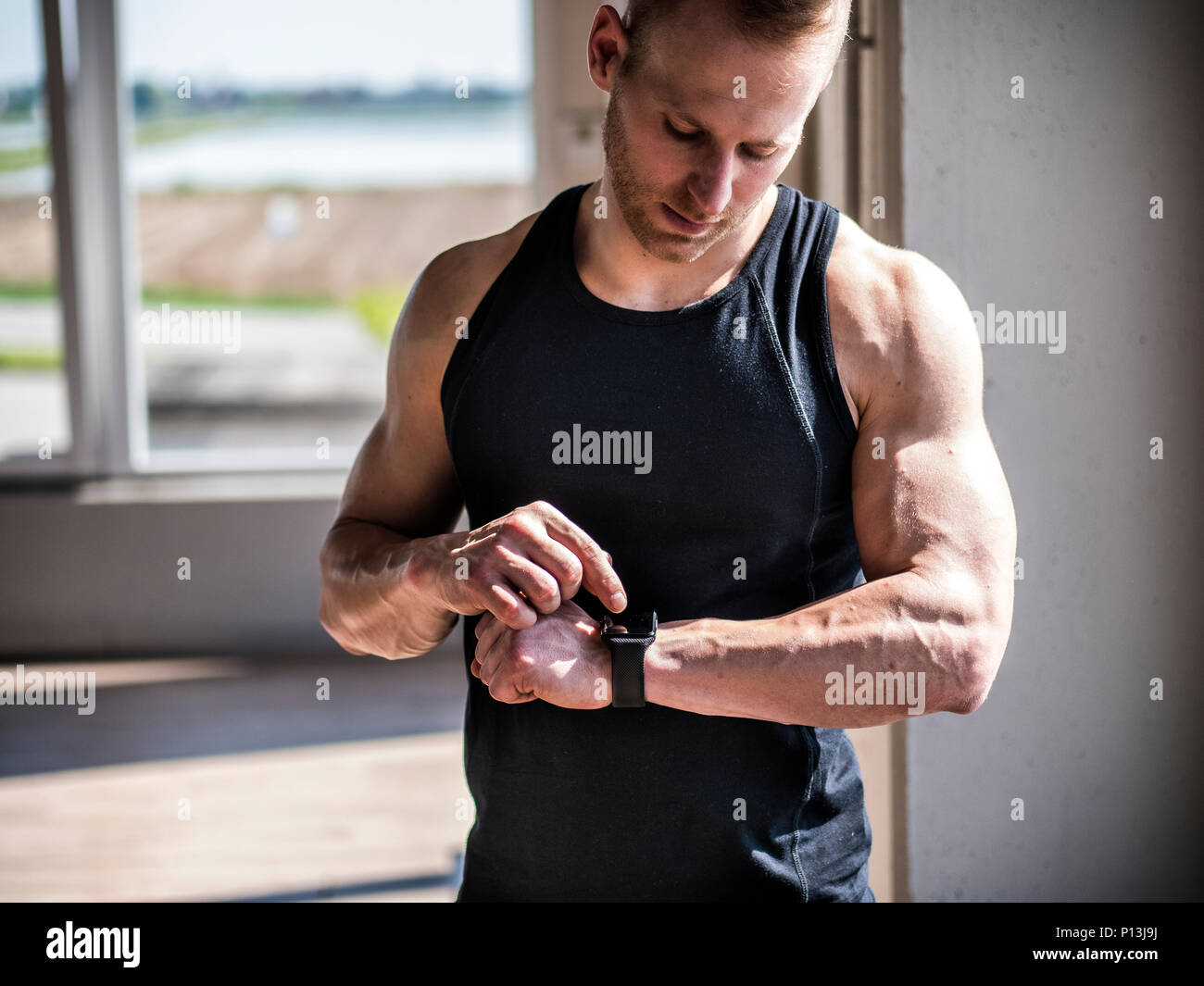 Junge Mann in der Turnhalle überprüfung Sportuhr Stockfoto