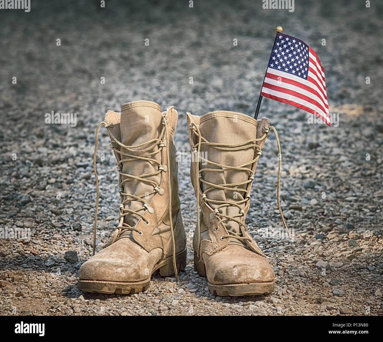 Alte militärische Bekämpfung der Stiefel mit der amerikanischen Flagge. Felsigen Kies Hintergrund. Memorial Day oder Veterans Day Konzept. Stockfoto