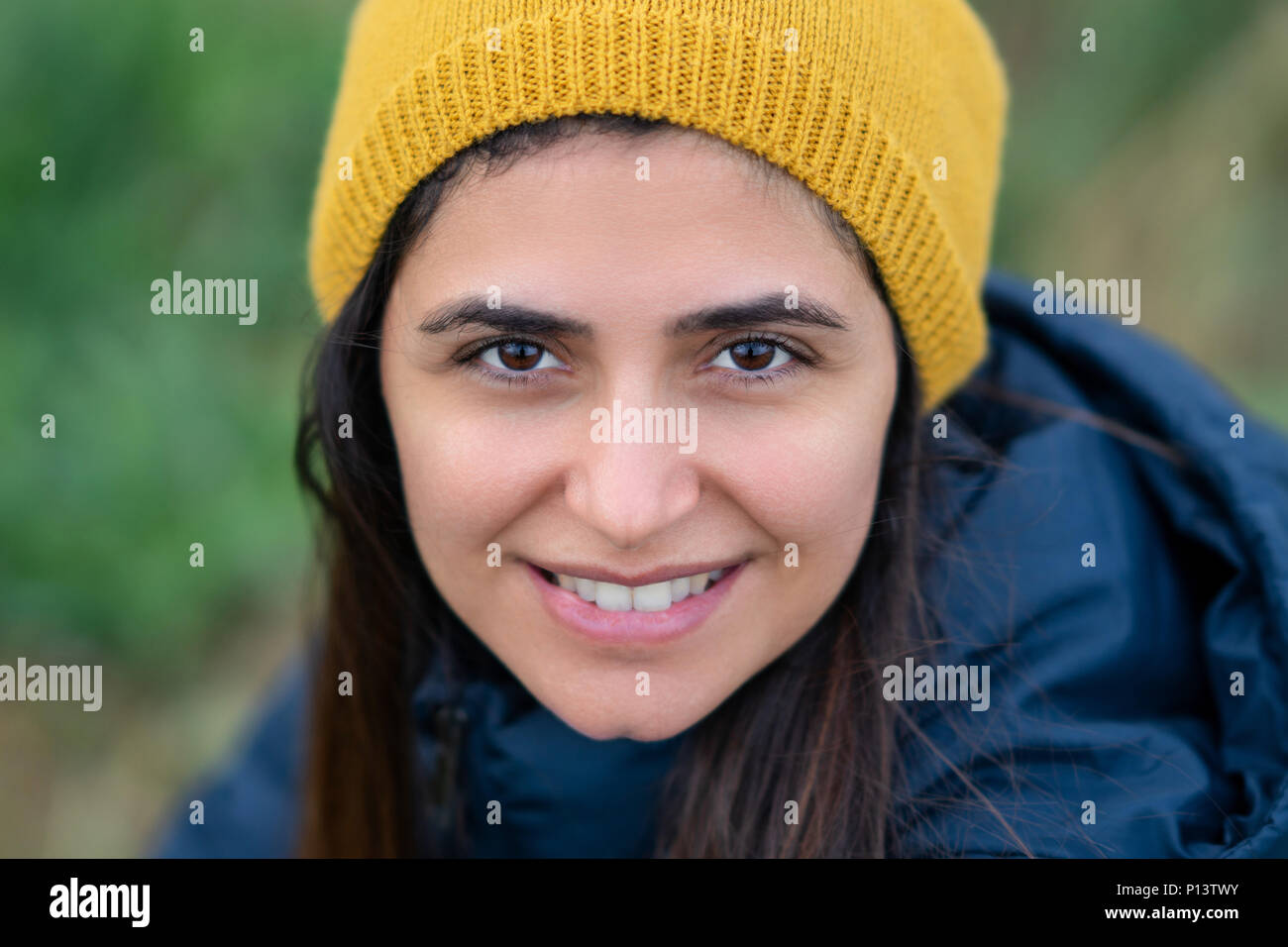 Junge schöne Brünette Frau lächelnd mit gelbe Baskenmütze. Stockfoto