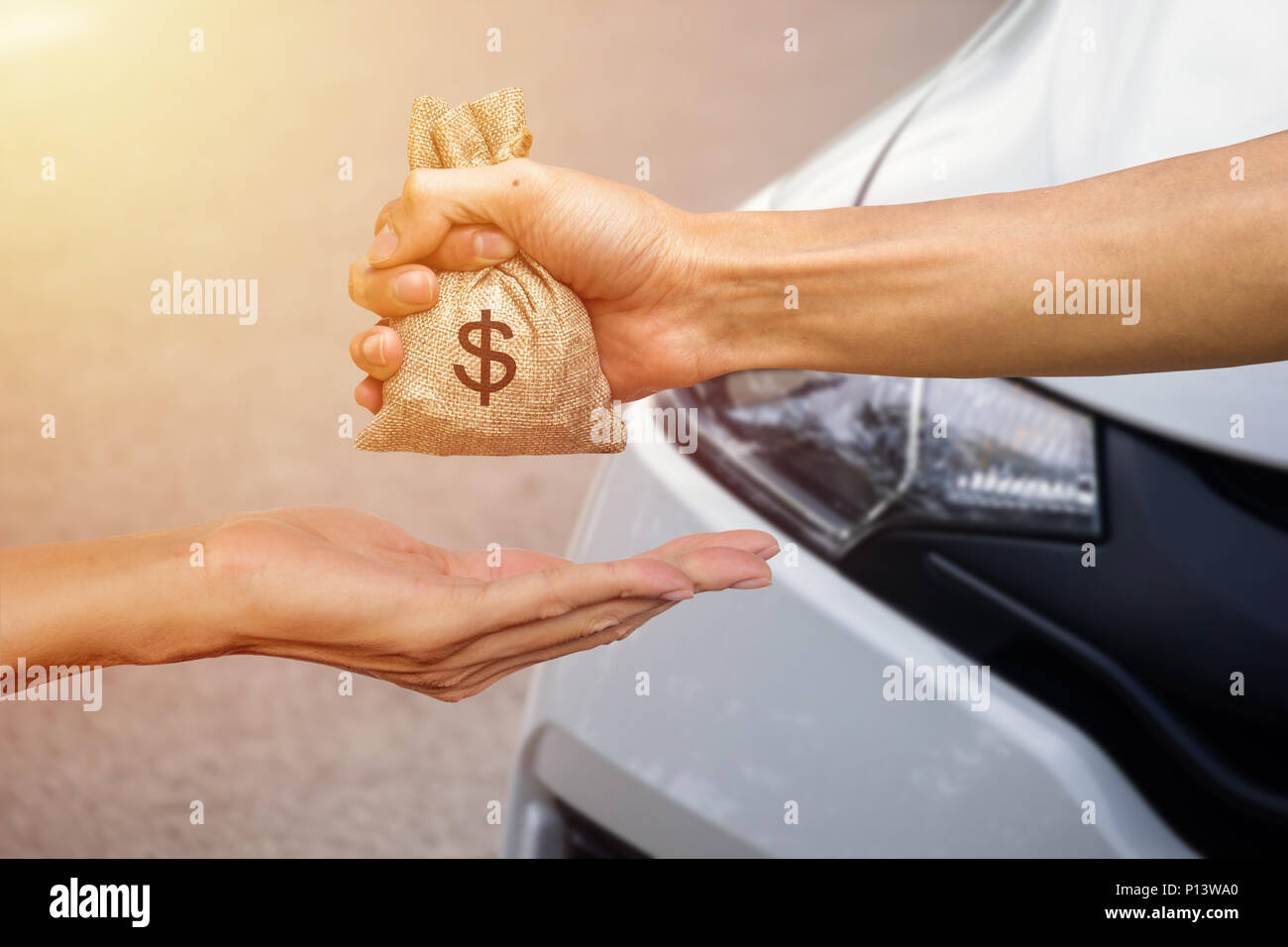 Ein Mann hand mit einem Geld geben, an eine andere Person für den Kauf von neuen Autos. Darlehen für neues Auto Konzept. Konzeptionelle geben Geld an jemand anderen zu n Exchange Stockfoto