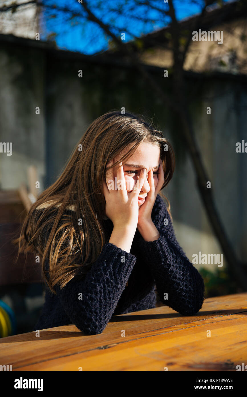 Eine traurig und deprimiert süsse kleine Mädchen sitzen draußen am Tisch. Einsamkeit und Depression Konzept. Stockfoto