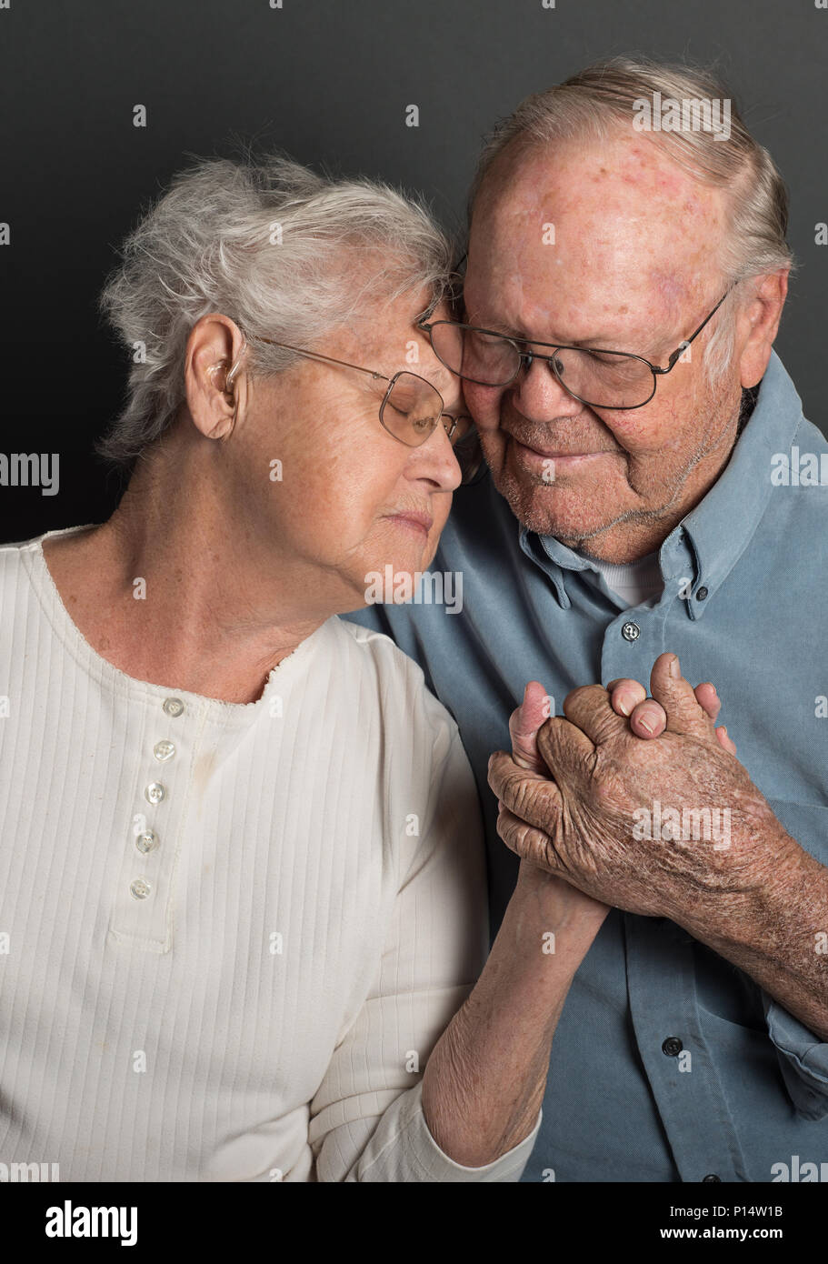 Senior Paar Hände halten in einem Tender Loving in Schwarzweiß umfassen, sowohl Brillen, Mann unrasiert Stockfoto