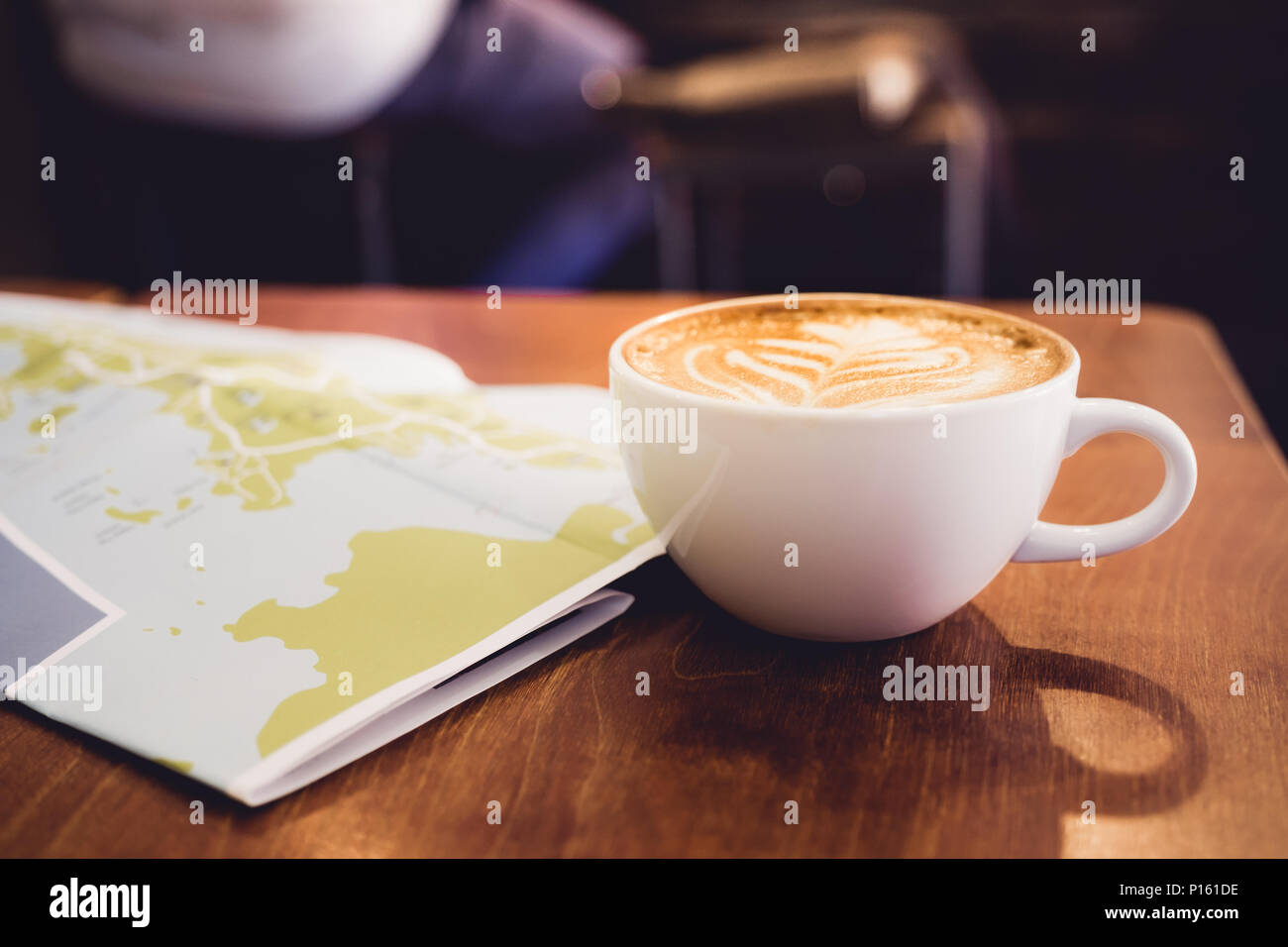 Weiß Kaffeetasse mit Latte Art mit Reisekarte auf braunem Holz Tisch, Freizeit Aktivität Stockfoto