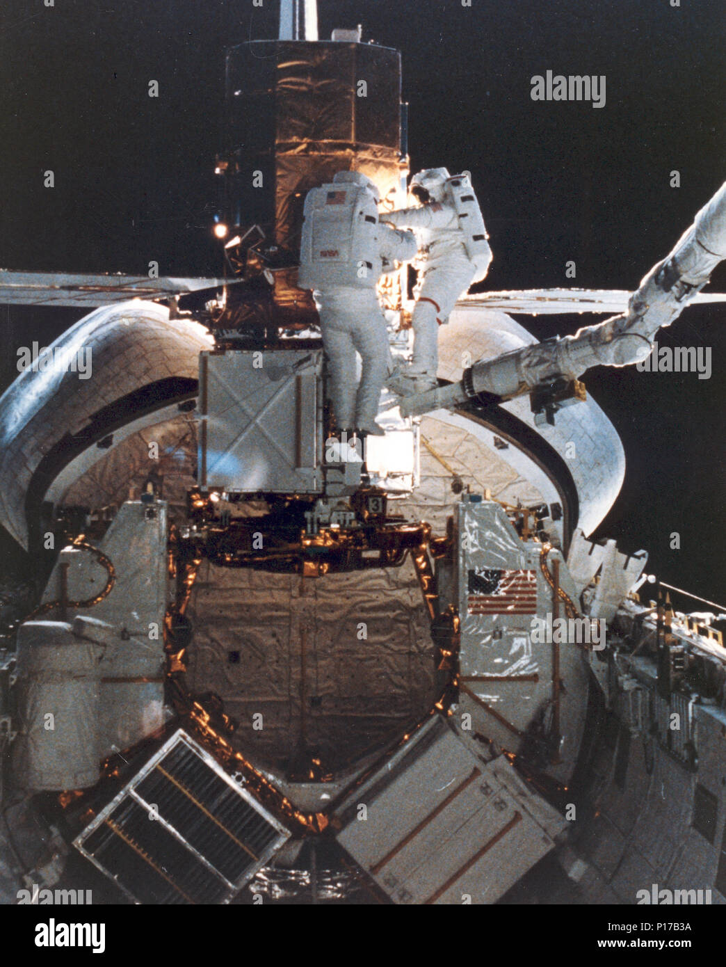 STS-41C Astronauten George D. Nelson, rechts, und James D. van Hoften Teilen eine Reparatur Aufgabe auf die Gefangenen Solar Maximum Mission Satelliten (SMMS) im hinteren Ende der Herausforderer Cargo Bay. Die beiden Mission Specialist die mobile Fuß Zurückhaltung und der Remote Manipulator System (RMS) als 'Cherry Picker" Gerät für die, die sich bewegen. Später, die RMS hob den SMMS in Raum noch einmal. Stockfoto