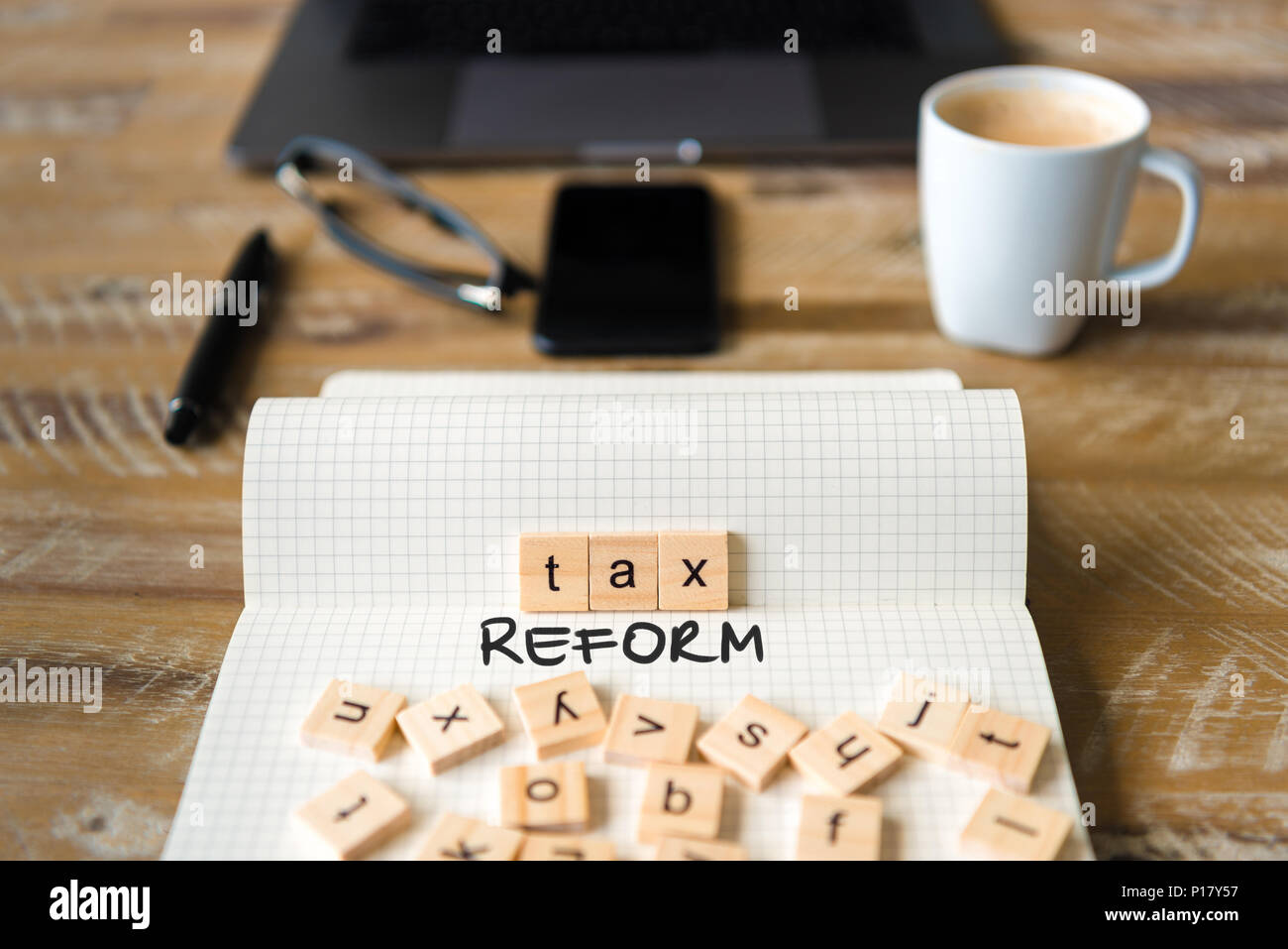 Nahaufnahme auf das Notebook um Vintage Schreibtisch Oberfläche, front Fokus auf Holzblöcke mit Buchstaben, die Steuerreform Text. Stockfoto