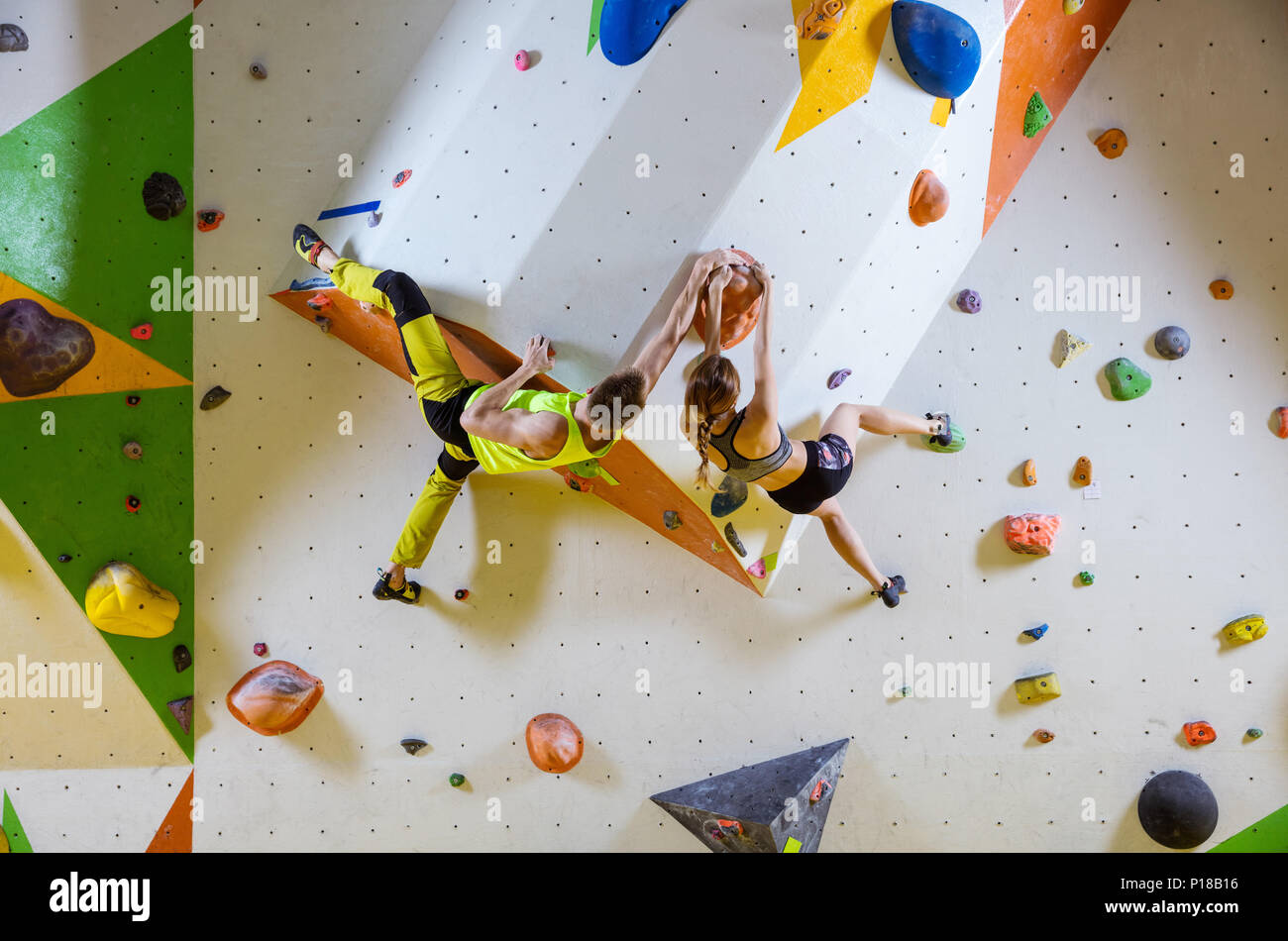 Kletterer in Kletterhalle. Junges Paar klettern Bouldern Probleme (Routen), packende gleichen Haltegriff. Stockfoto