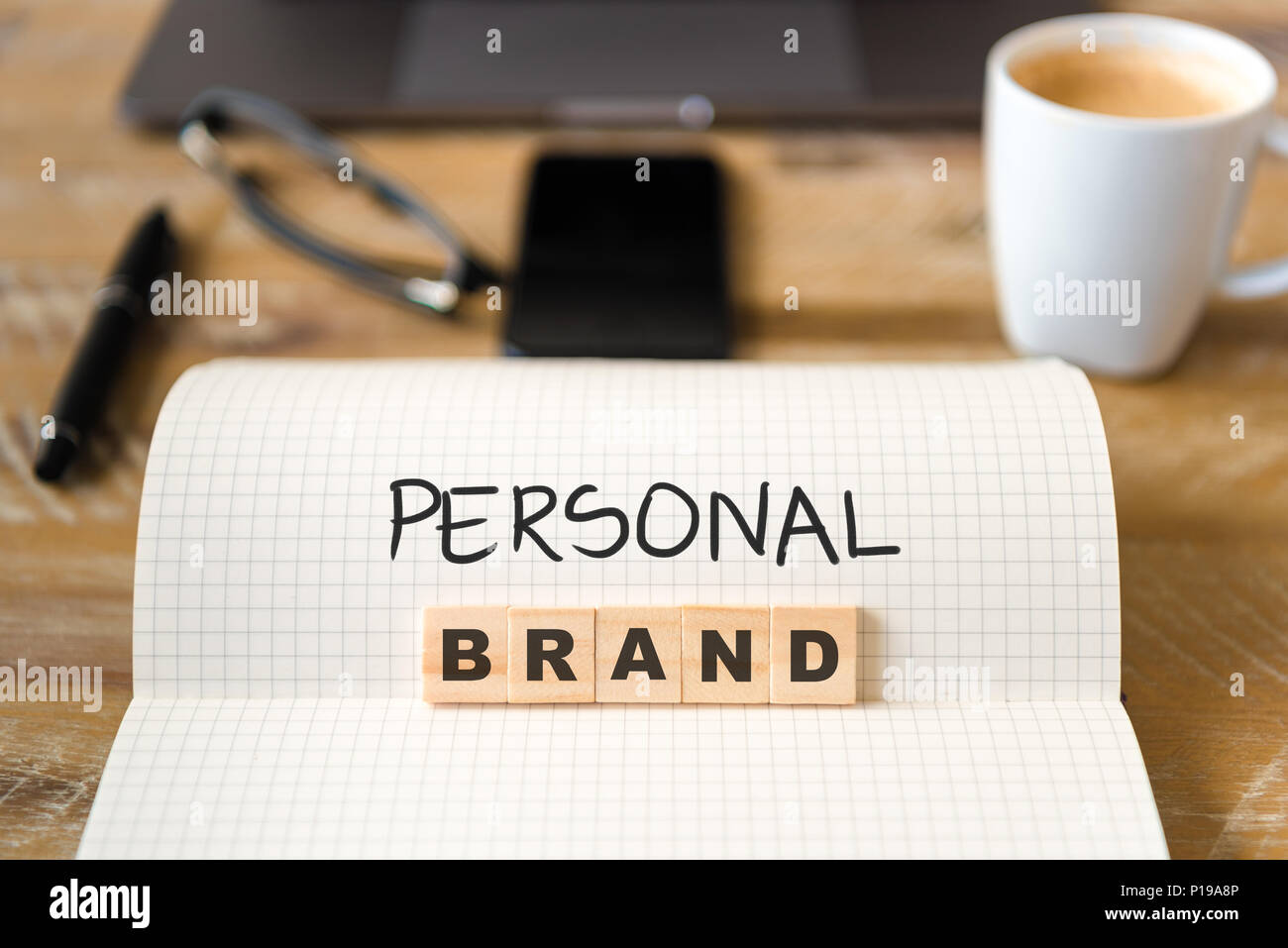 Nahaufnahme auf das Notebook um Vintage Schreibtisch Oberfläche, front Fokus auf Holzblöcke mit Buchstaben, persönliche Marke Text. Stockfoto