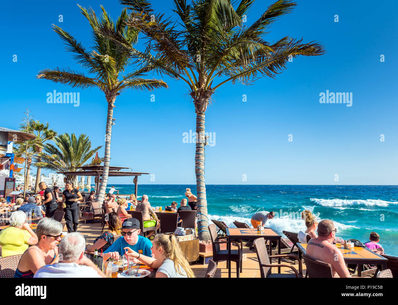 Puerto del Carmen, Spanien - 29. Dezember 2016: Touristen genießen Getränke und Landschaft im Café La Ola in Puerto del Carmen, Spanien. Puerto del Carmen ist der m Stockfoto