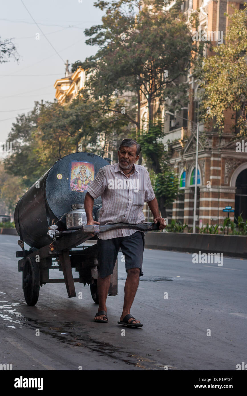 MUMBAI, INDIEN - Dezember 4,2016: Alter Arbeiter ziehen waren Warenkorb in der Mitte von Mumbai Straße Stockfoto