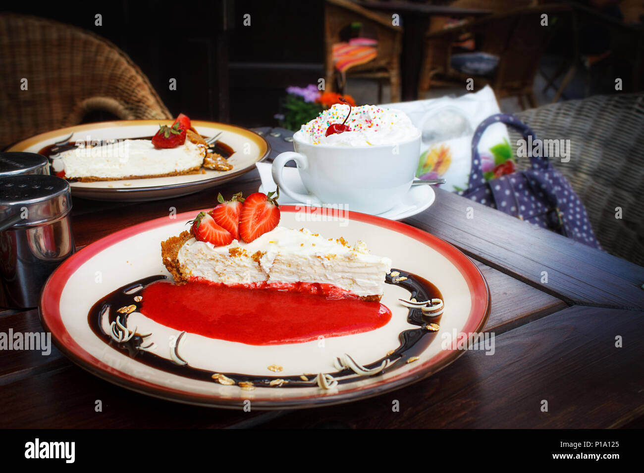 Käsekuchen mit frischen Erdbeeren auf Platte und einer Tasse Wiener ...