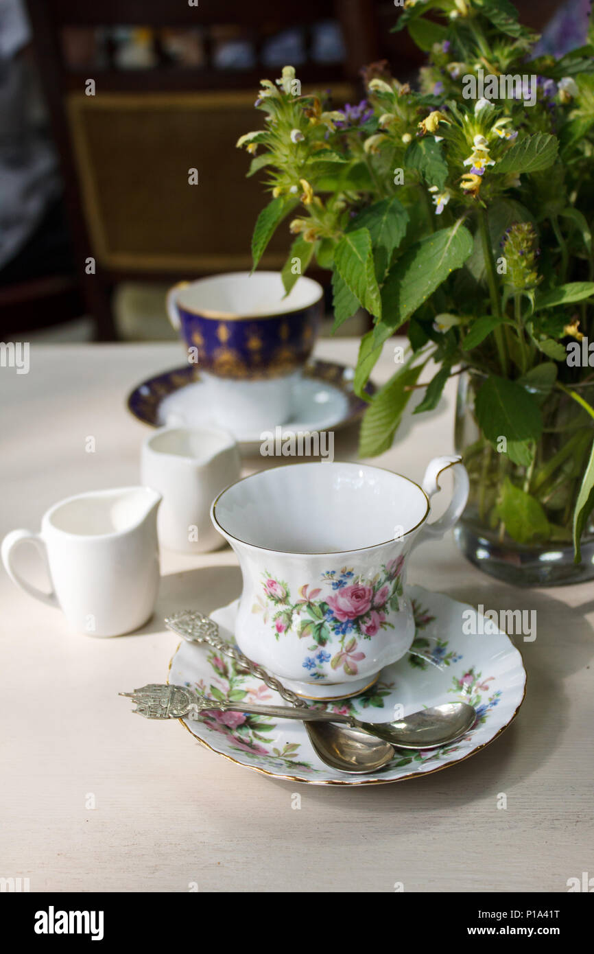 Vintage Porzellan Kaffeetasse, silber Kaffee Löffel und Blumenstrauß aus Sommer Wildblumen auf einen Tisch. Entspannenden gemütlichen alten Haus auf dem Land retro Atmosphäre. Stockfoto