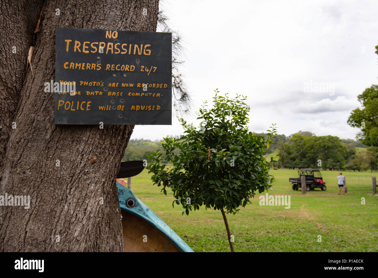 Ein No Trespassing Zeichen auf einer Farm im Norden von NSW mit einer Person im Hintergrund Stockfoto