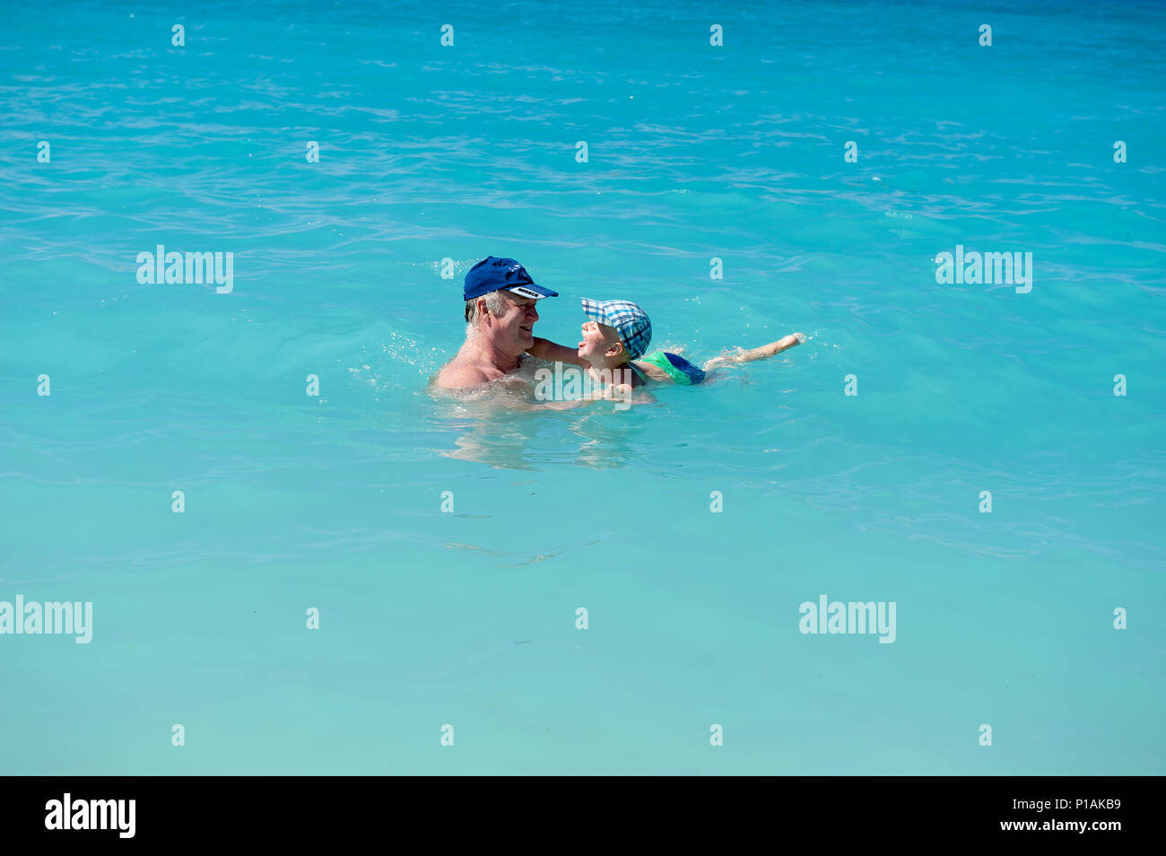 Zwei Jahre alten Sohn schwimmen mit seinem Großvater auf einem Strand, Ag. Kiriakis Strand, Kefalonia, Ionische Inseln, Griechenland, Europa Stockfoto